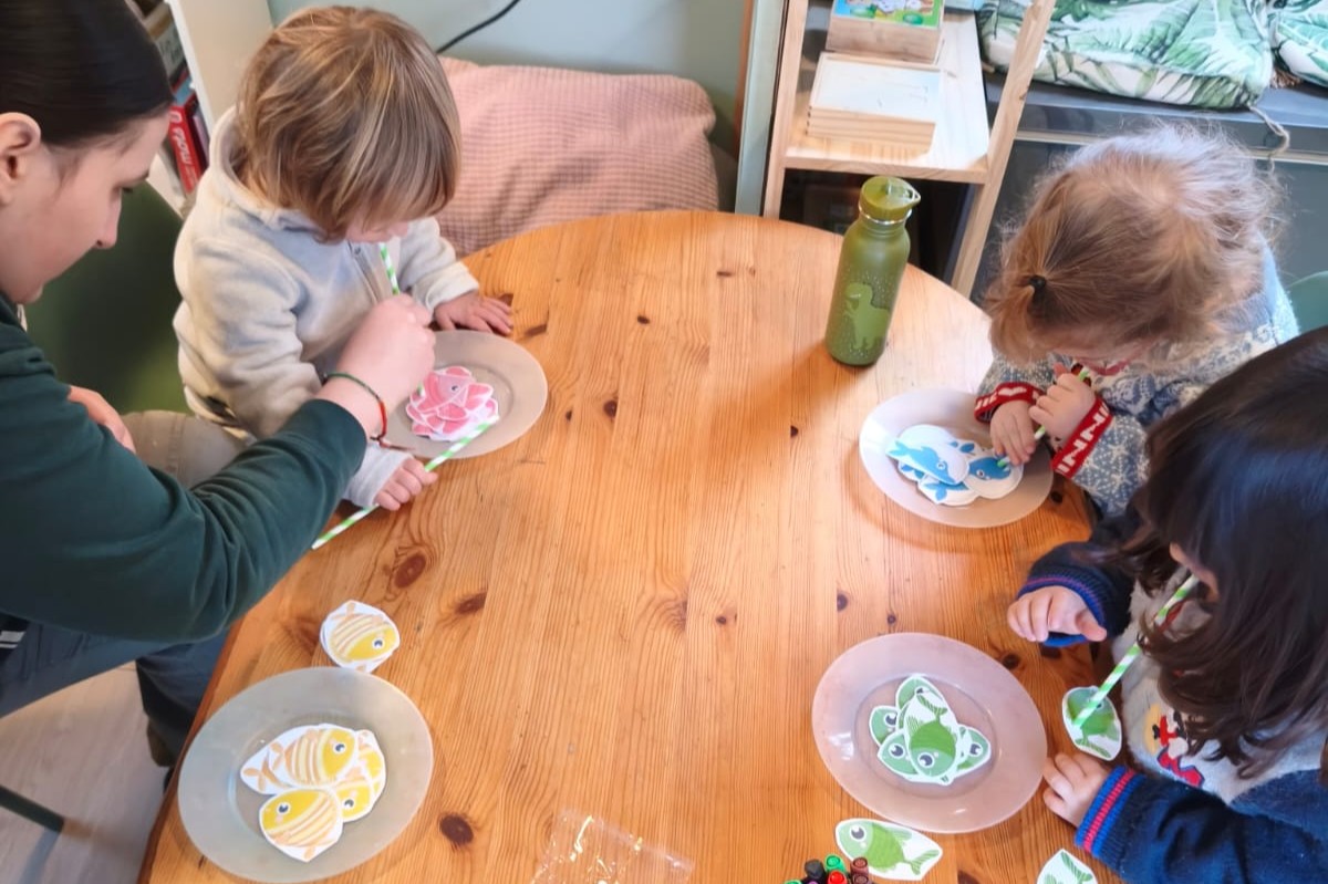 Enfants qui soufflent dans des pailles pour déplacer des poissons en papier